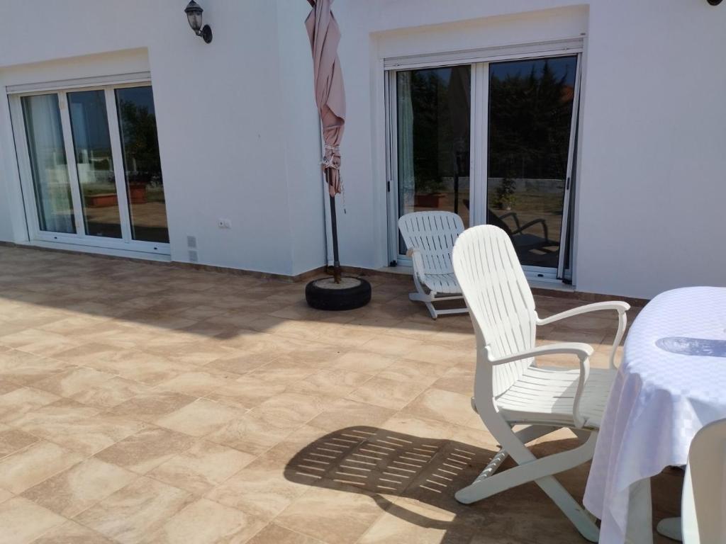 a patio with two white chairs and a table at Summer and Winter Villas in Néa Tríglia