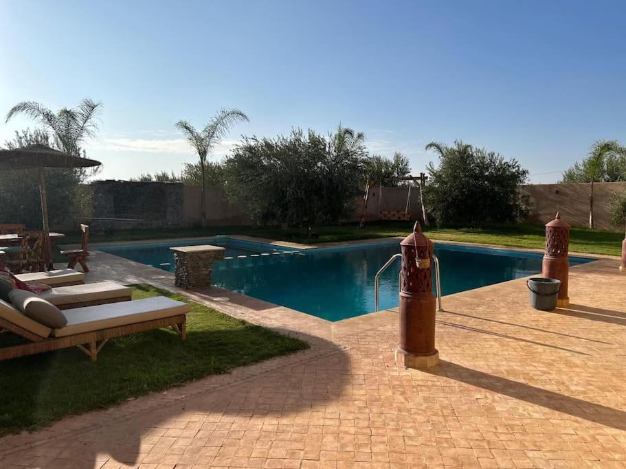 a swimming pool with a table and a bench next to it at Magnifique villa à Marrakech in Marrakech