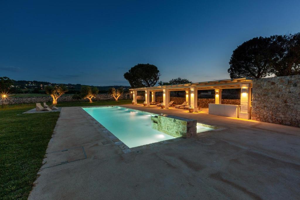uma piscina em frente a uma casa à noite em Masseria Santella Luxury B&B em Cassano delle Murge