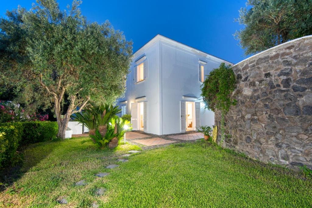 a white house with a stone wall and a yard at Il Lauro Luxury Villa in Ischia