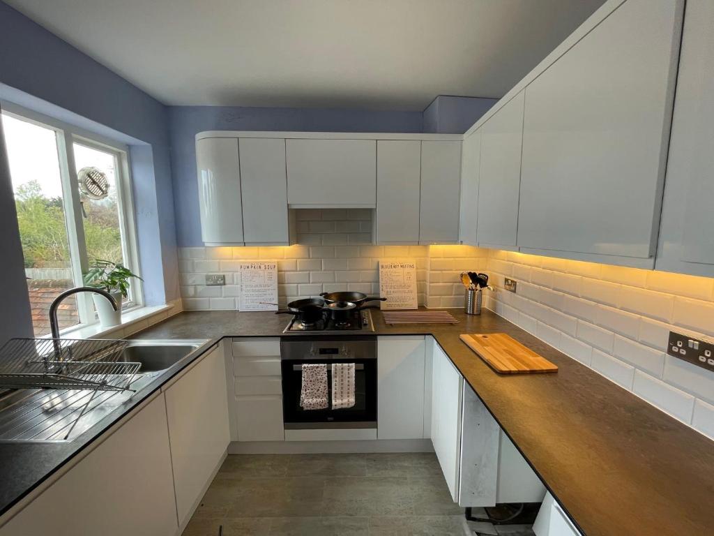 a kitchen with white cabinets and a wooden counter top at Quintessential 2 Bedroom Apartment in the heart of Cookham in Maidenhead