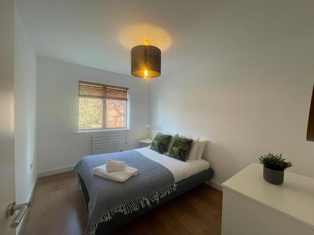 MAIDENHEAD Stylish and modern 2 bedroom apartment في ميدينهيد: غرفة نوم صغيرة بها سرير ونافذة