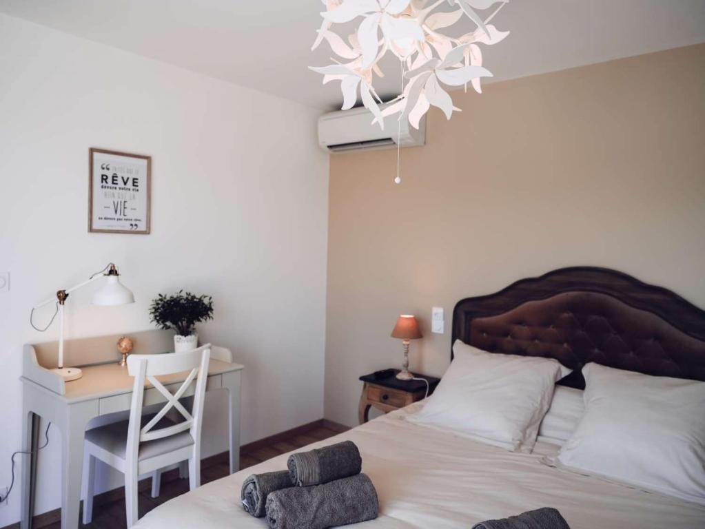 a bedroom with a bed and a desk and a chandelier at Villa Maurine - Piscine chauffée - Spa - Clim - Salle de Fitness in Castelnau-de-Montmiral