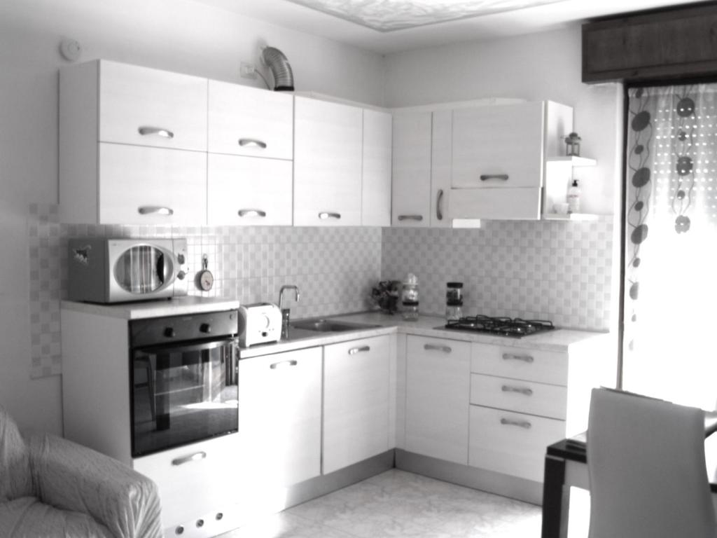 cocina con armarios blancos y fogones en Charming 2-Bed House in Albaro for every Traveler, 