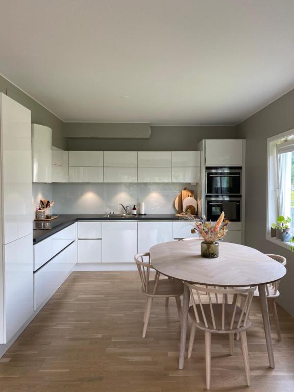 a kitchen with white cabinets and a table and chairs at Moderne leilighet, 3 sov, parkering. in Trondheim