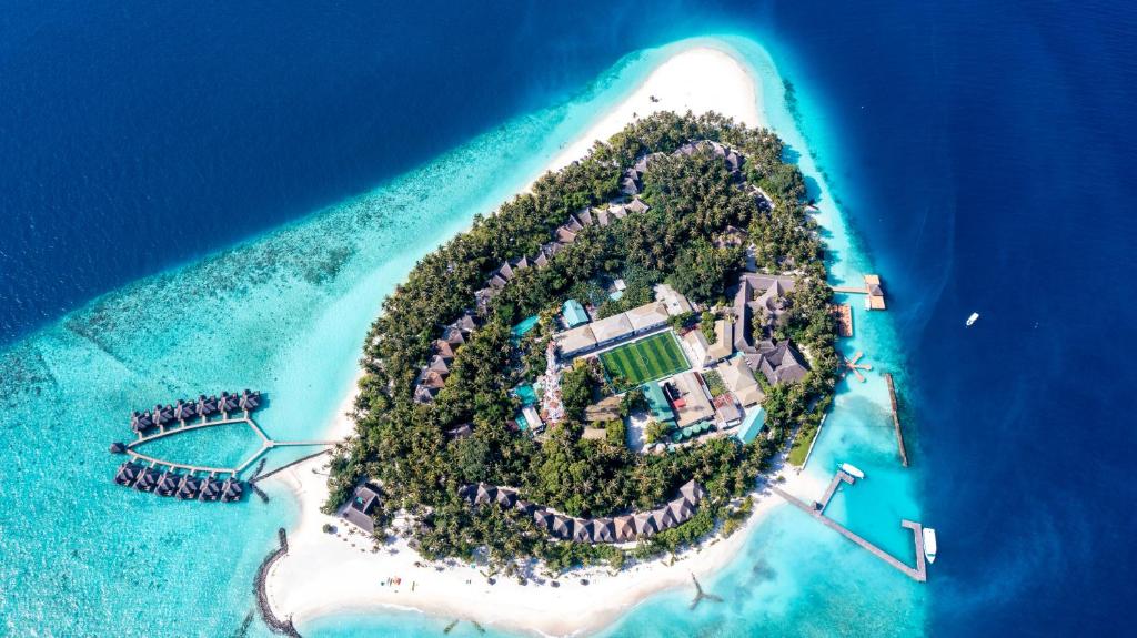 an island with a resort in the middle of the ocean at Fihalhohi Maldives in South Male Atoll