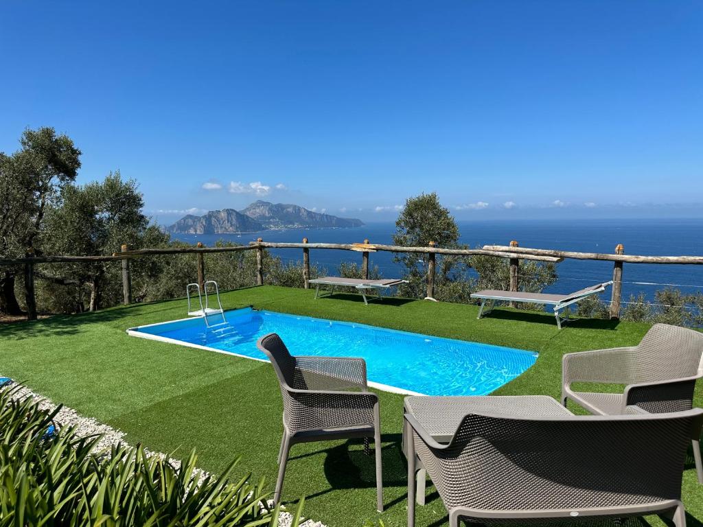 a backyard with a swimming pool and chairs and the ocean at Farm seaview on Capri in Termini