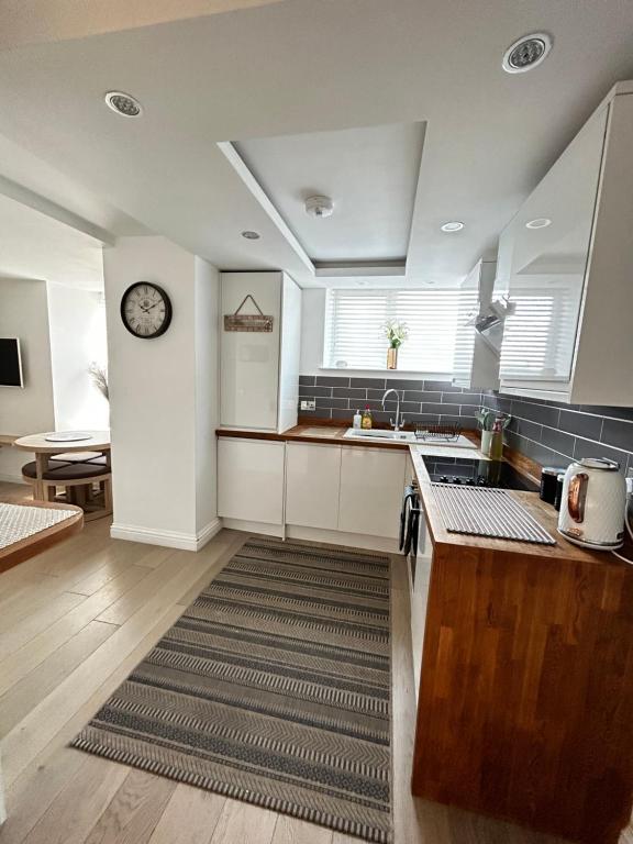 a kitchen with white cabinets and a clock on the wall at Homely Beachside Apartment in Newquay Town Centre! in Newquay