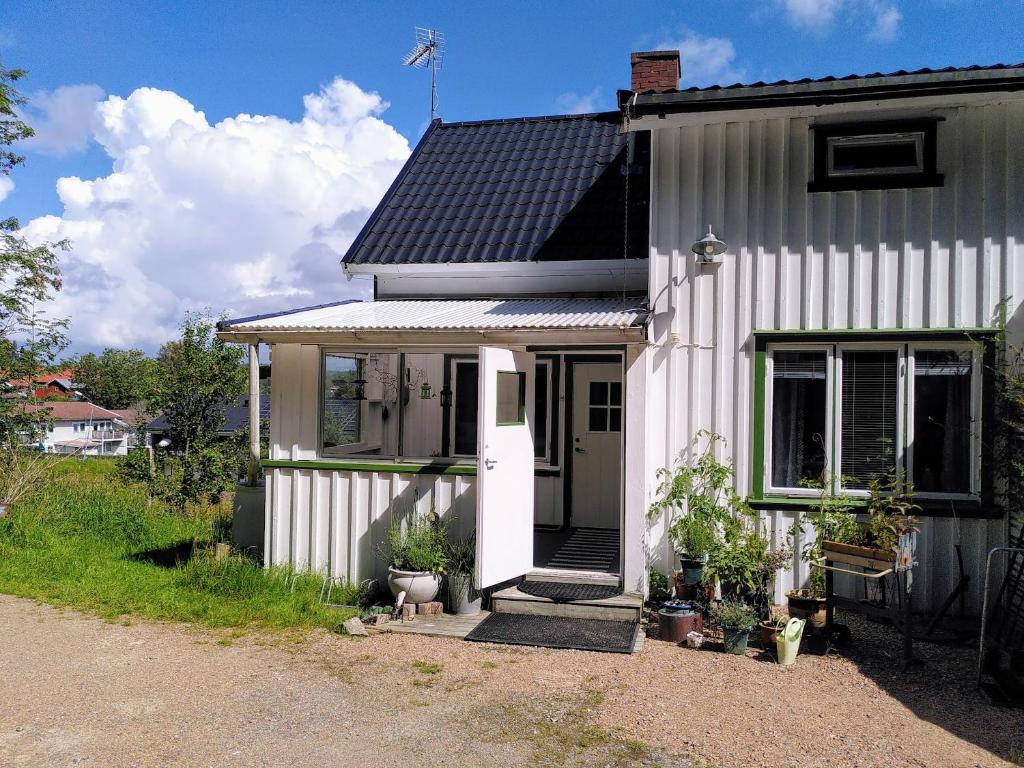une petite maison blanche avec un toit noir dans l'établissement Lägenhet naturnära i Henån, à Henån