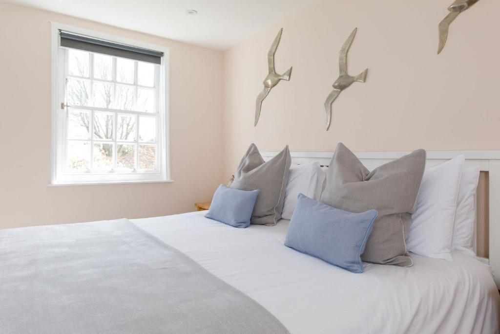 a white bed with blue pillows and birds on the wall at Snowdrop Cottage in Ditchling