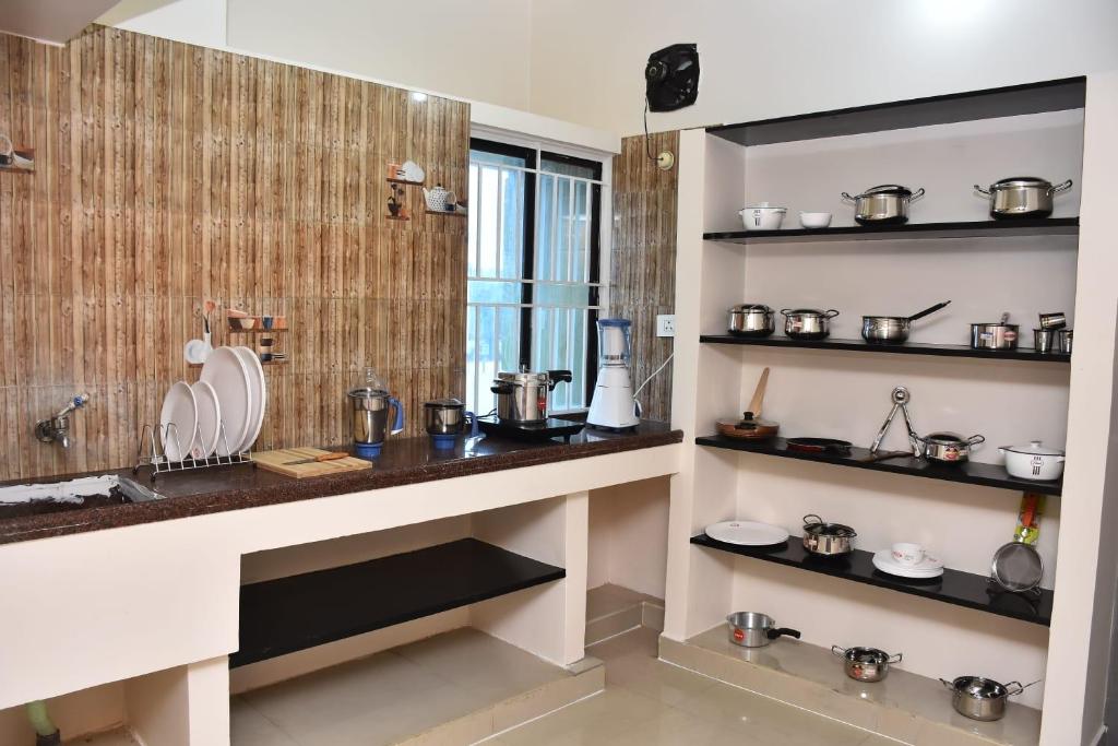 a kitchen with a counter and shelves with pots and pans at Amsam Family Stay in Thanjāvūr