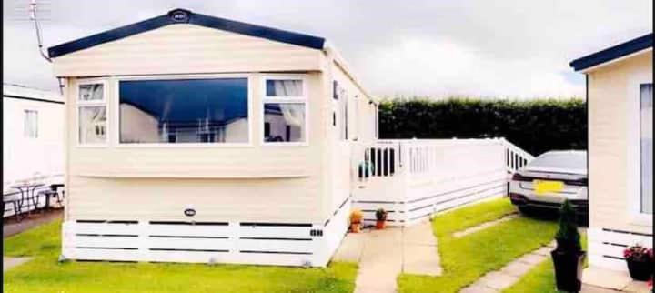 a small white shed with a window in a yard at Beautiful 3 bed Static Caravan with Snowdon views in Caernarfon in Caernarfon