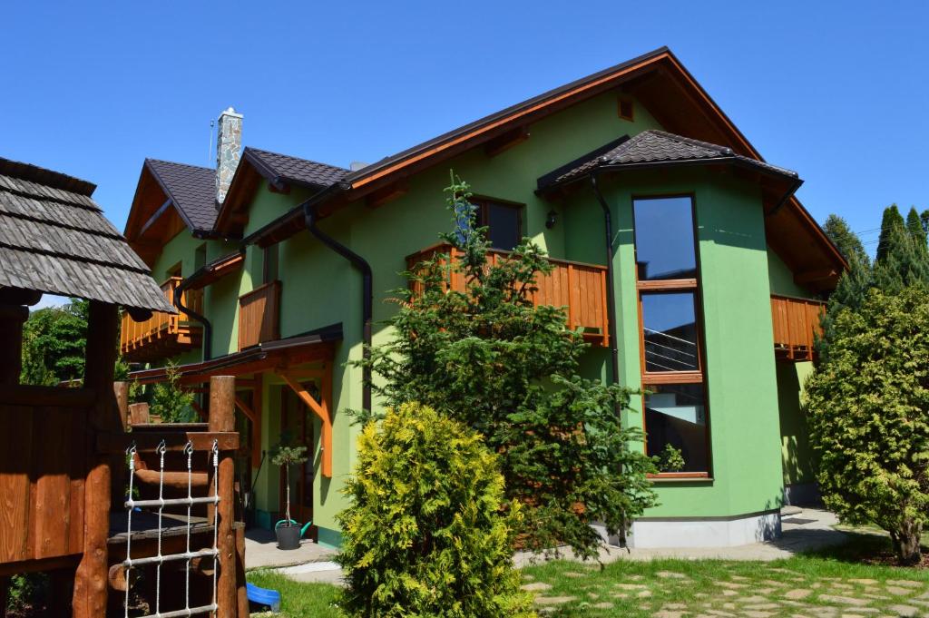 a green house with a brown roof at Ubytovanie Pri zvonici in Liptovský Mikuláš