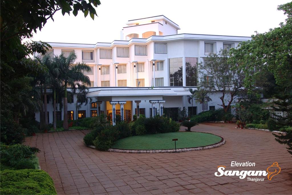 un gran edificio blanco con un césped verde delante de él en Sangam Hotel, Thanjavur, en Thanjāvūr