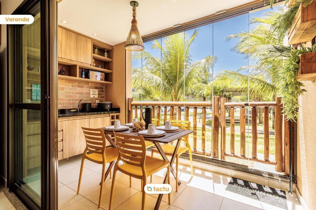 a kitchen and dining room with a table and chairs and a balcony at Lindo térreo ao lado da piscina no VG Sun Cumbuco in Cumbuco