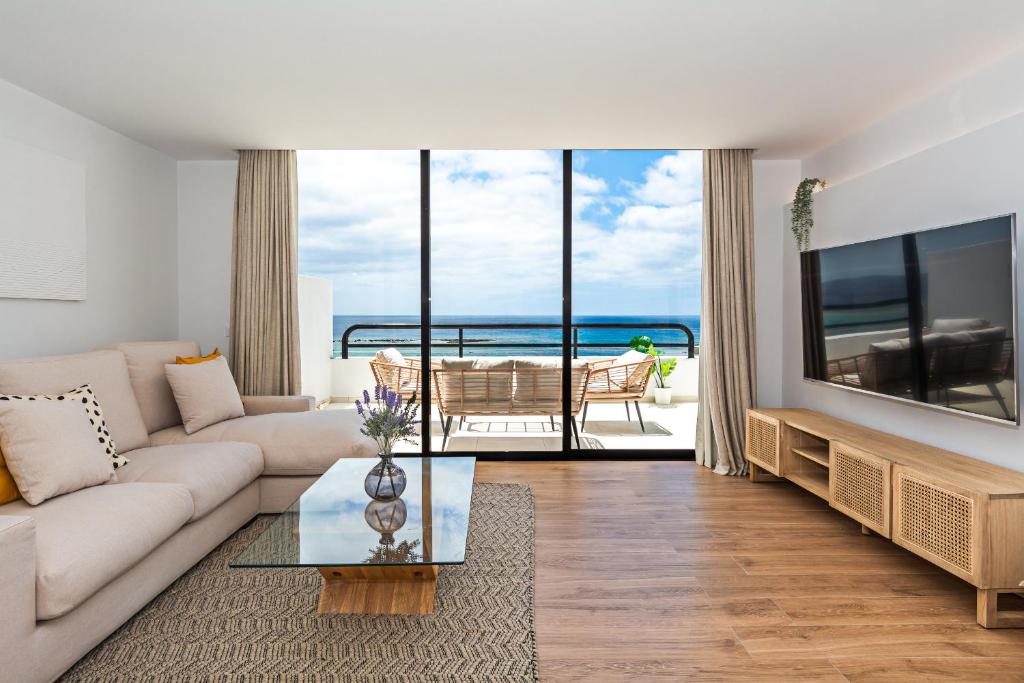 a living room with a white couch and a large tv at Luxury Beach Views 2BR House - Private Parking in Arrecife