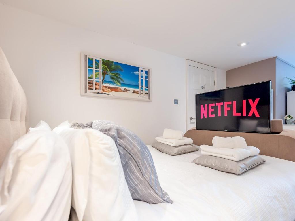 a bedroom with a white bed with a netflix sign on the wall at Pass the Keys Hidden Gem Near Roundhay Park in Leeds