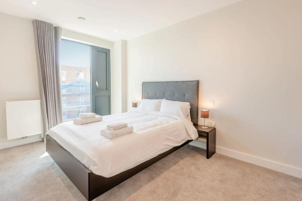 ein weißes Schlafzimmer mit einem großen Bett und einem Fenster in der Unterkunft Modern Apartments in Brentford 2 minutes walk from Kew Bridge in Brentford