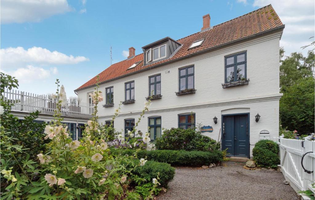 a white house with black windows and a white fence at 2 Bedroom Pet Friendly Apartment In Svaneke in Svaneke