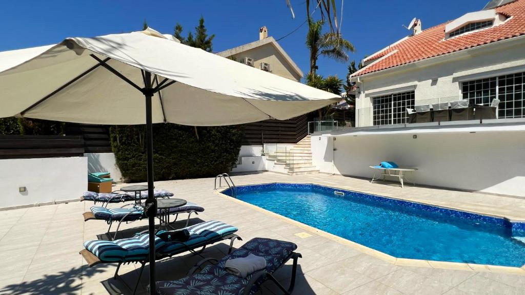 利馬索爾的住宿－Villa Sawa by Ezoria Villas，游泳池旁的遮阳伞和椅子