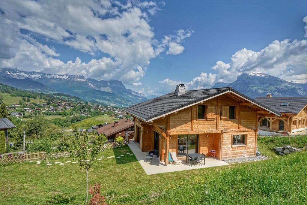 a log home with mountains in the background at Magnifique Chalet neuf 8 pers, 800 m télécabine Princesse Megeve in Combloux