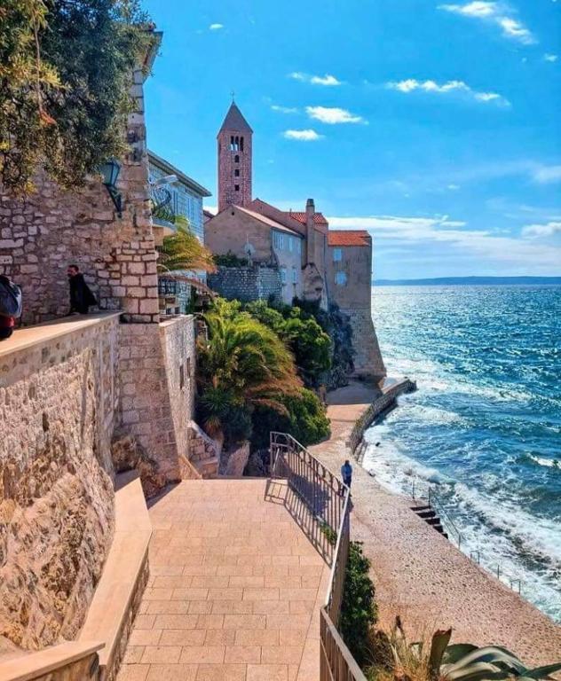 a walkway next to the ocean next to a building at Old Town Arbia in Rab