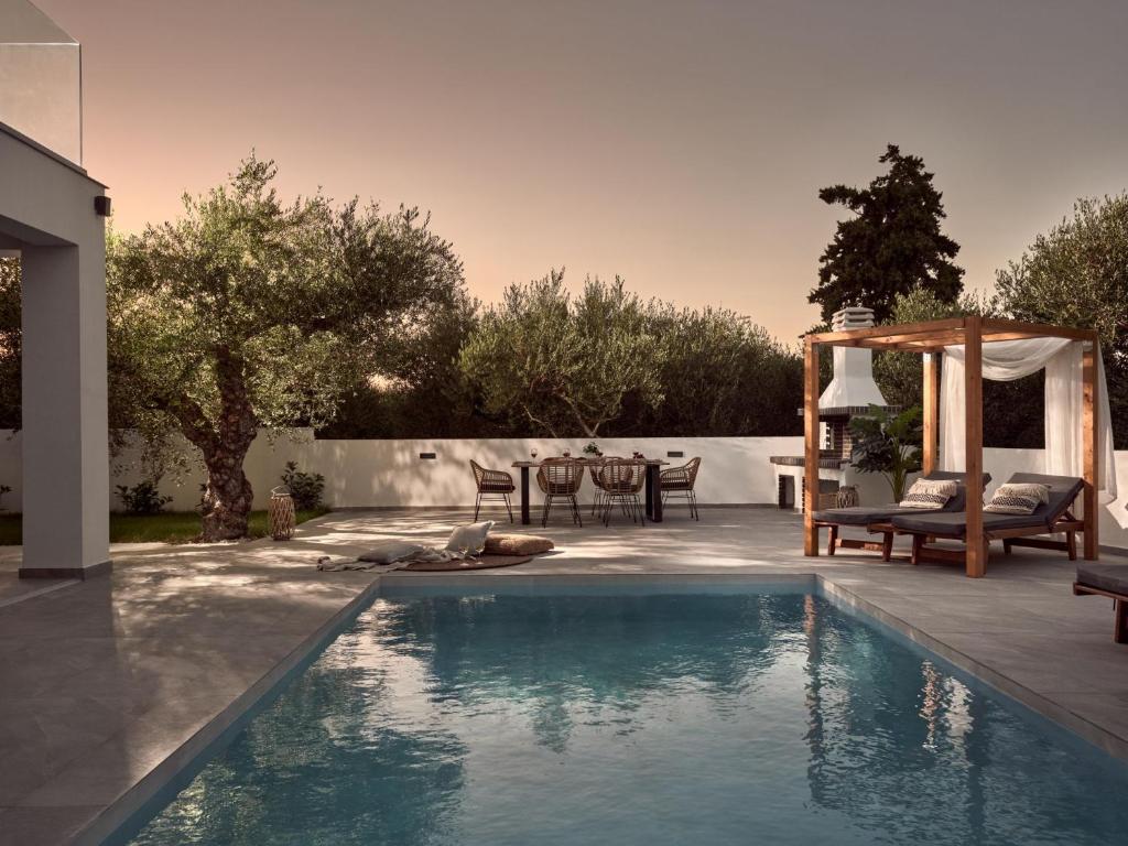 a swimming pool in a backyard with a table and chairs at Kapodistria Luxury Villas - 3-Bedroom Villas with Private Pool, by ZanteWize in Planos
