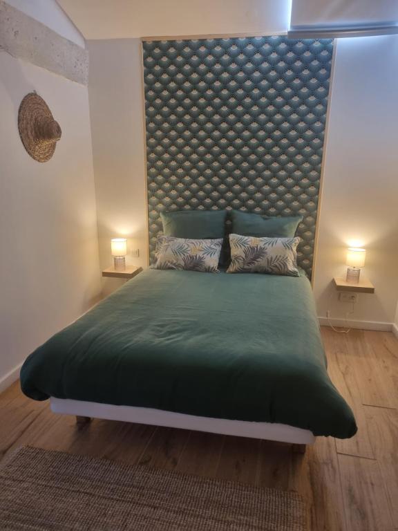 a bedroom with a large green bed with a padded headboard at ENTRE VENTOUX ET LUBERON Chambre d'hôte in Sault-de-Vaucluse