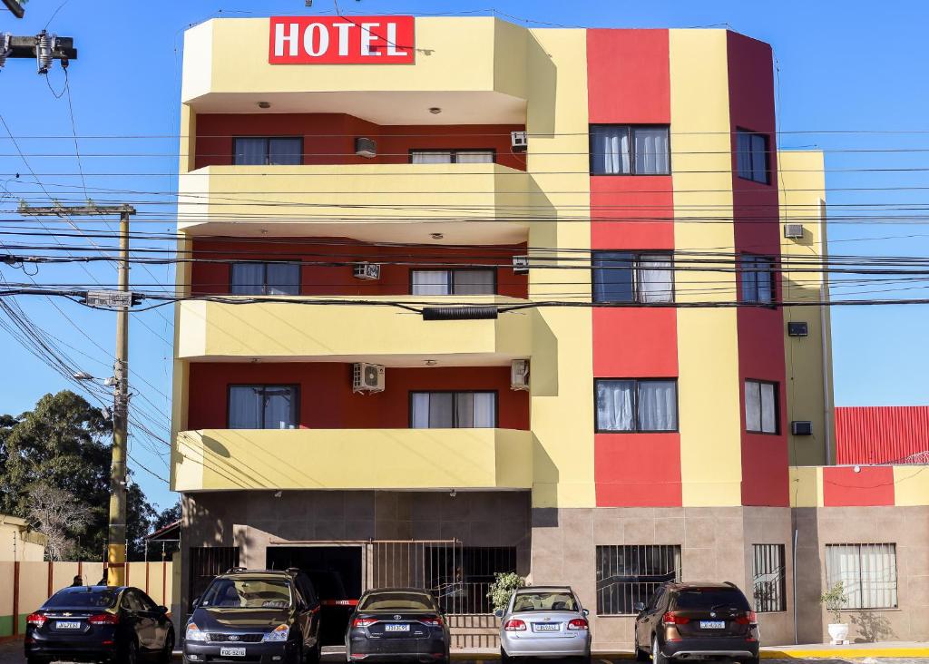 Arpini Hotel في ريو غراندي: فندق فيه سيارات تقف امامه