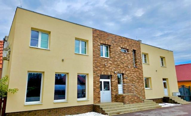 - un grand bâtiment en briques avec une porte blanche dans l'établissement Penzión Alexandra, à Hokovce