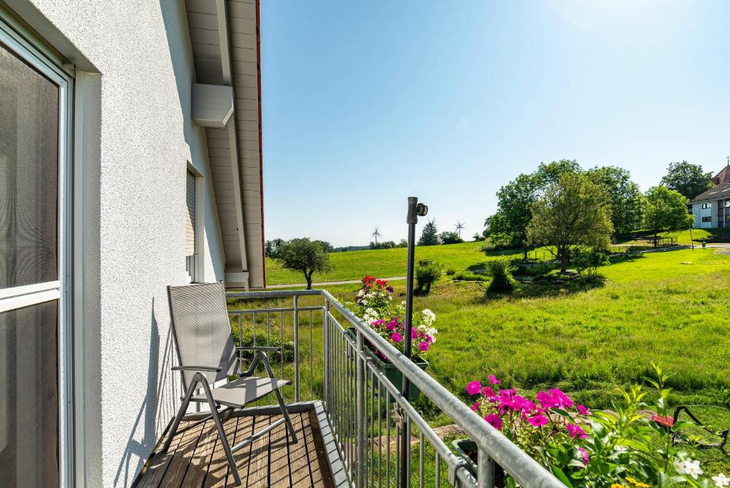 a porch with a chair and flowers and a field at Schwalbenhof Dreßler und Duss für 2 Personen in Bad Herrenalb