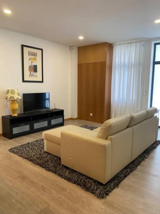een woonkamer met een witte bank en een televisie bij Apartamento em braga in Braga