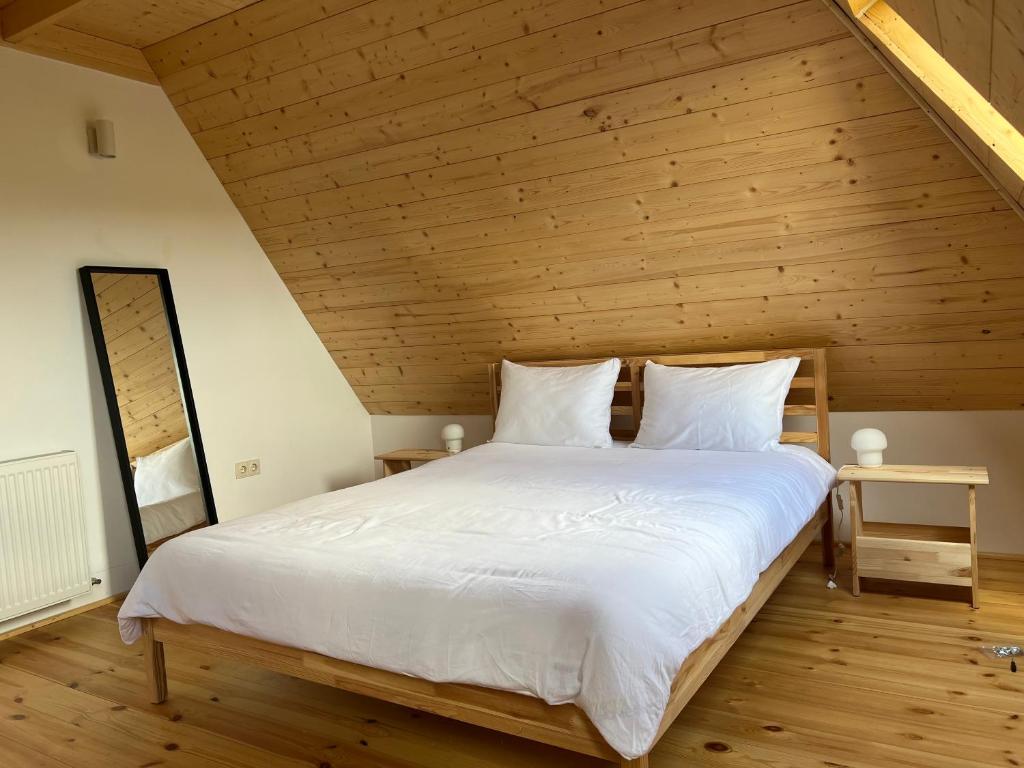 a bedroom with a large white bed with a wooden ceiling at arra housing near Bistrita in Şintereag