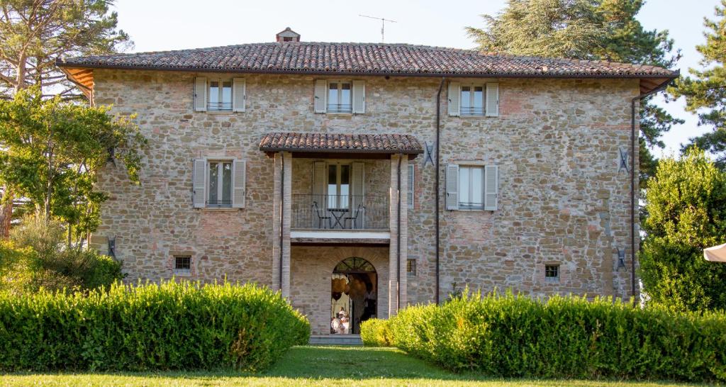 una vecchia casa in pietra con porta e balcone di Coldimolino Resort a Gubbio