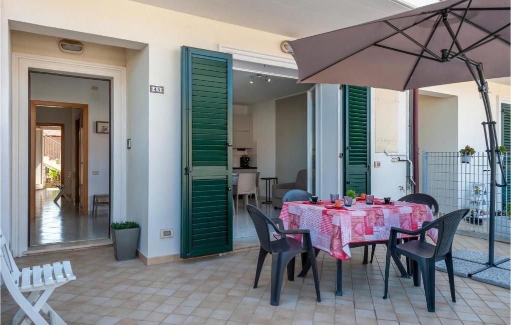 eine Terrasse mit einem Tisch, Stühlen und einem Sonnenschirm in der Unterkunft Nice Home In Porto Recanati With Wifi And 2 Bedrooms in Porto Recanati