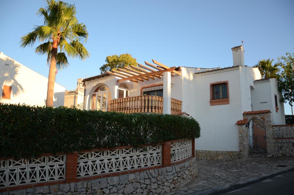 a white house with a palm tree and a fence at CHALET INDEPENDIENTE COn VISTAS AL MAR in Peniscola