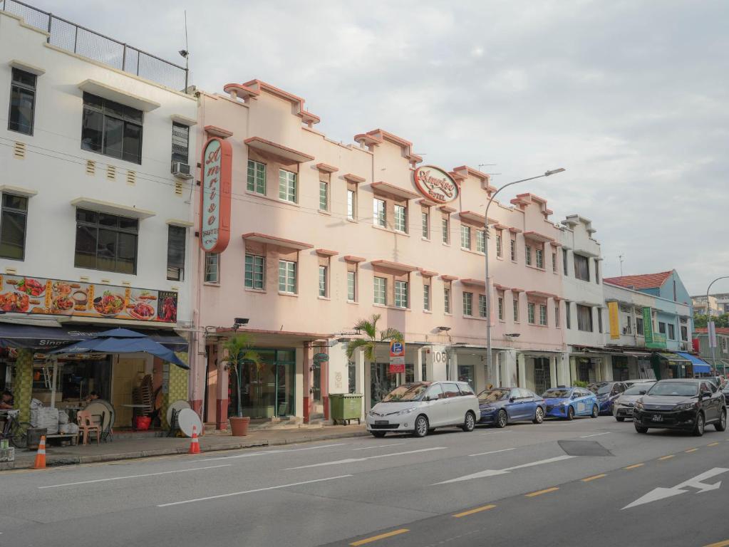 a street with cars parked in front of a pink building at Amrise Hotel in Singapore