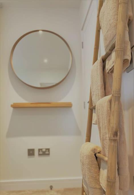 a mirror on a wall next to a ladder with towels at THE PAD by the beach Penthouse apartment with sunset and city views in Bournemouth