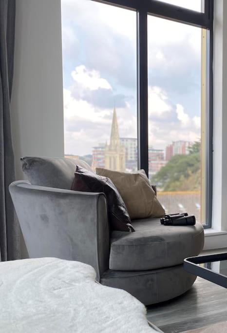 a couch sitting in front of a large window at THE PAD by the beach Penthouse apartment with sunset and city views in Bournemouth