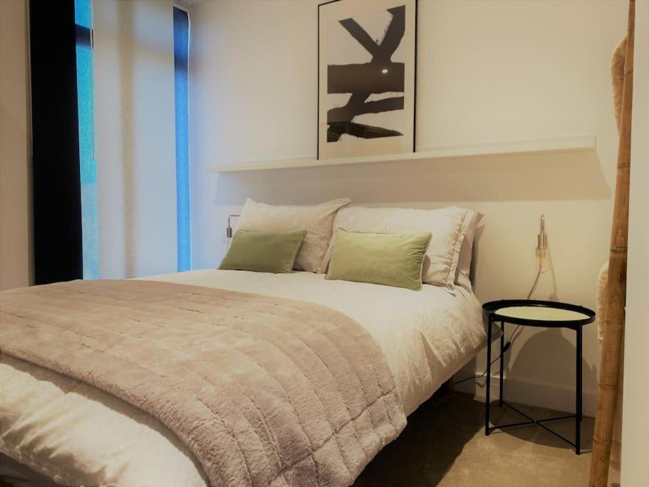 a bedroom with a large bed with a table at THE PAD by the beach Penthouse apartment with sunset and city views in Bournemouth