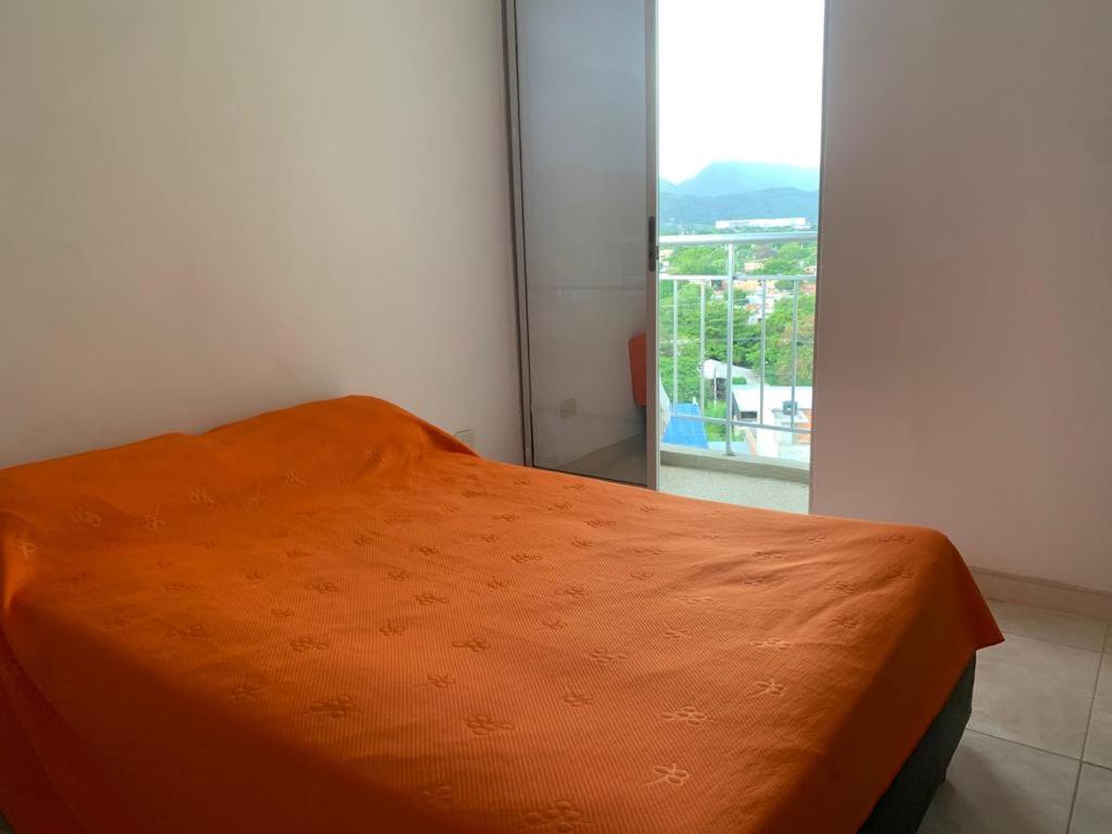 - un lit avec une couverture orange dans une chambre avec une fenêtre dans l'établissement Apto en Flandes Tolima., à Flandes