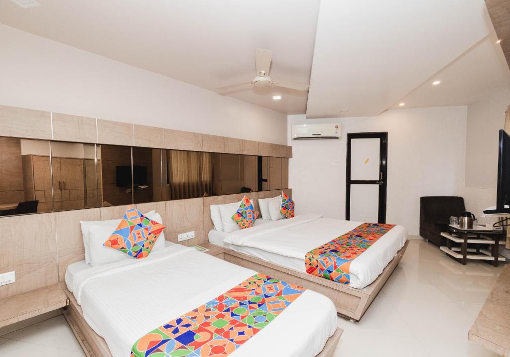 a hotel room with two beds and a desk at Hotel Amber Railway station in Vadodara