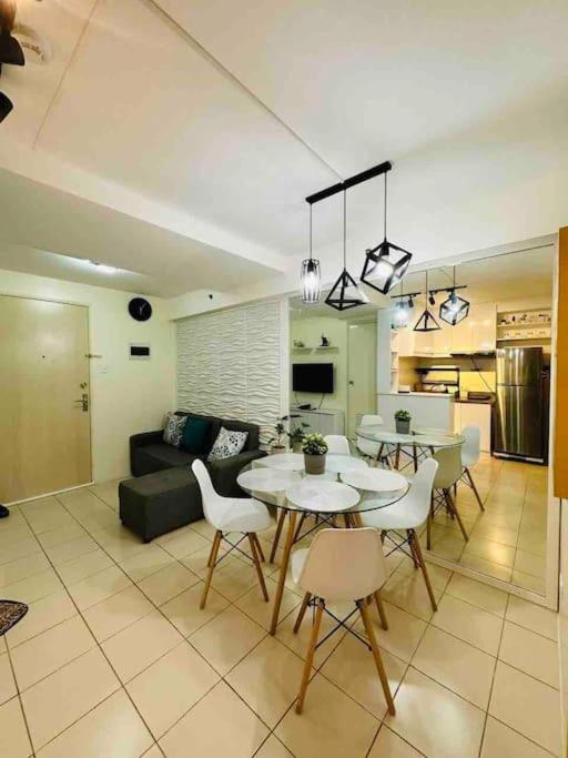 Condo in Ortigas (Kimea Suite) في مانيلا: غرفة معيشة مع أريكة وطاولات وكراسي