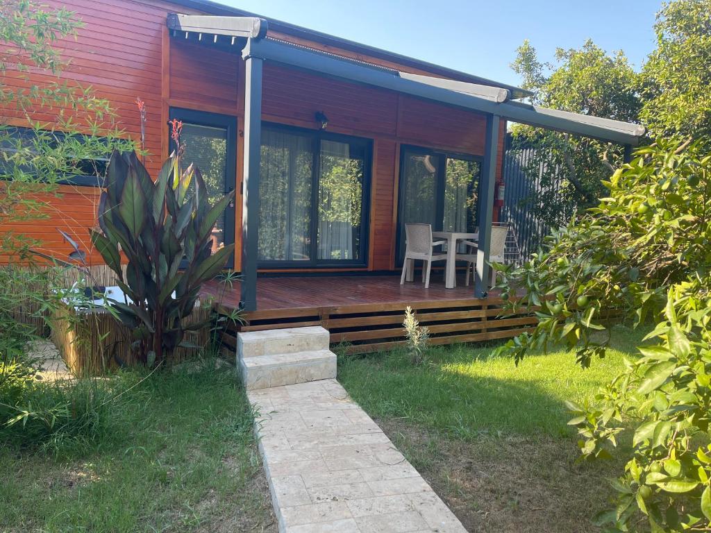 a red house with a deck with a table and chairs at JULYA TİNY HOUSE in Cıralı