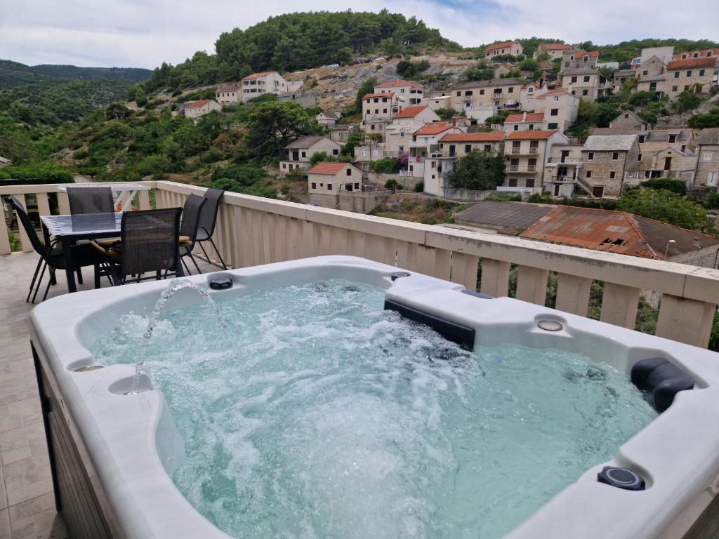 a hot tub on a balcony with a table and chairs at Apartment Mladinić Muse in Pučišća