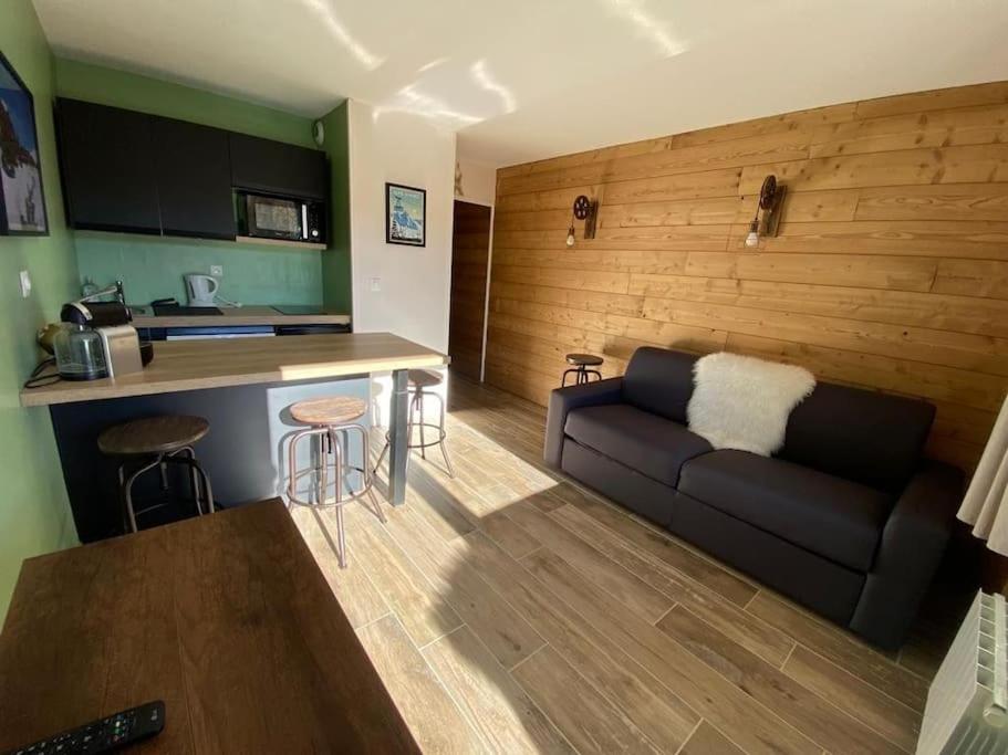 a living room with a couch and a kitchen at Au pied des pistes avec parking Entièrement rénové in LʼHuez