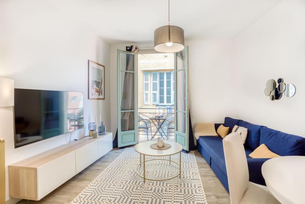 un salon avec un canapé bleu et une table dans l'établissement #44 1 BDR Flat Cap AC balcony 5mins walk to beach, à Nice