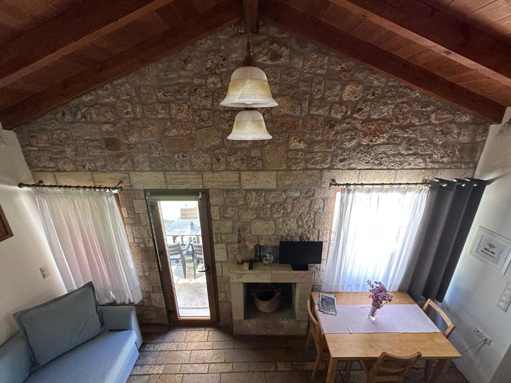 sala de estar con mesa y pared de piedra en Genari Beach Apartments, en Levendokhórion