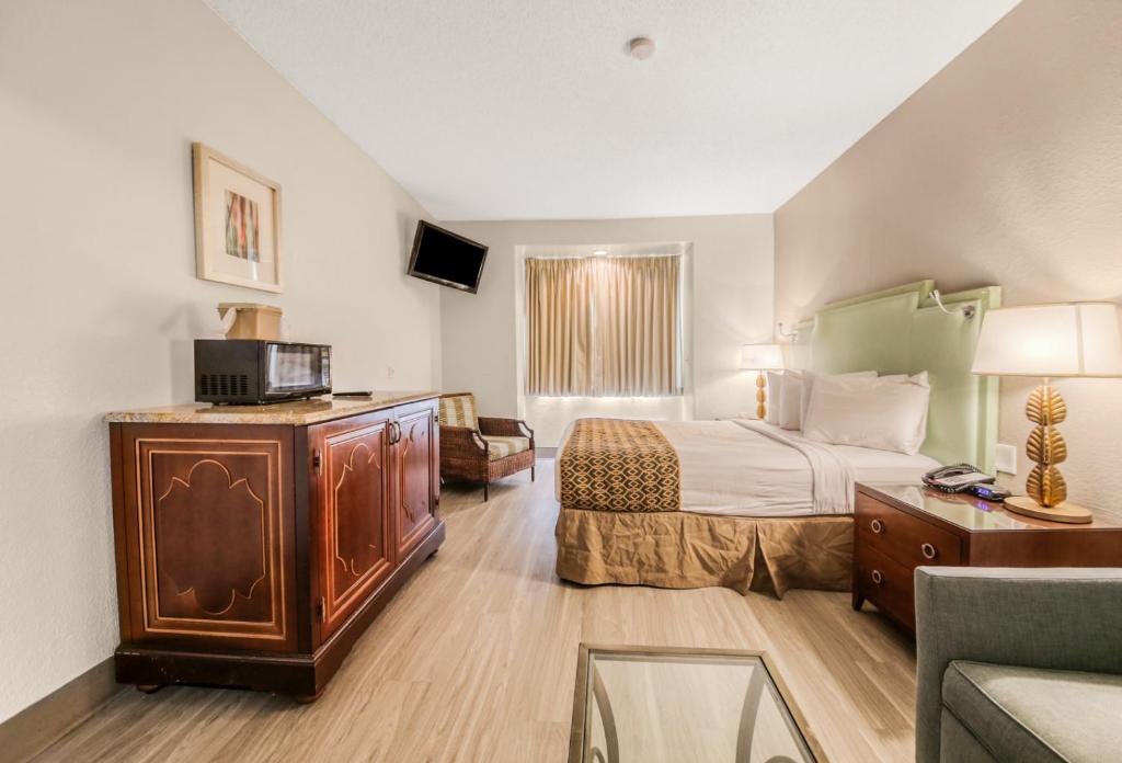 a hotel room with a bed and a tv at Baymont by Wyndham Orlando-International Dr-Universal Blvd in Orlando