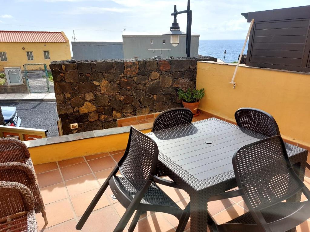 uma mesa e cadeiras numa varanda com o oceano em Alma y Sol em La Caleta